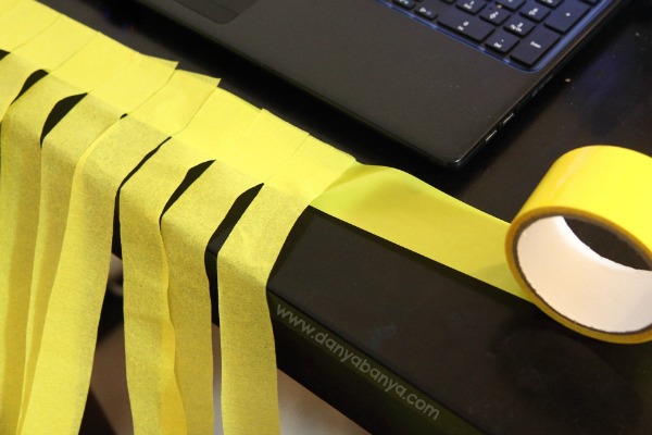 Sticking streamers to coloured tape to make Rapunzel wig