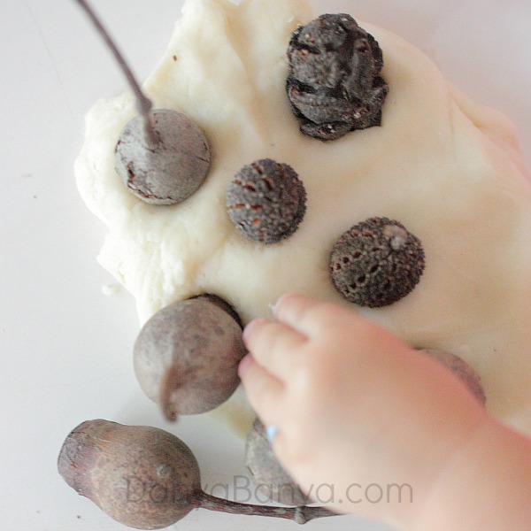 Toddler stamping with nature in playdough