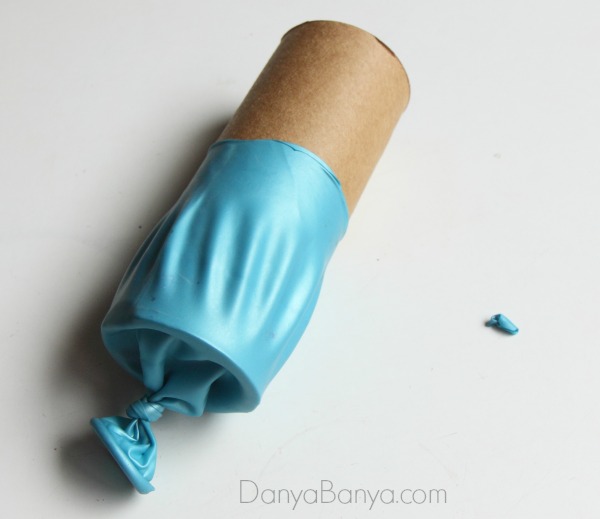 Stretch the balloon over a toilet paper roll or other cardboard tube