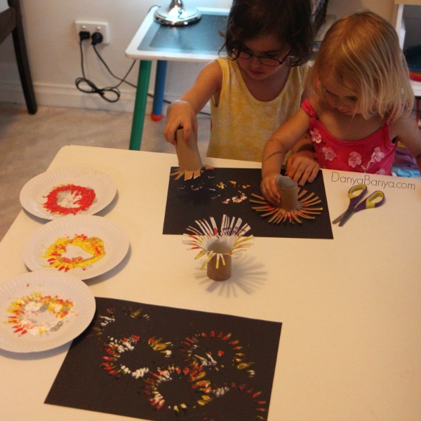 Toddler and preschooler painting fireworks with DIY toilet paper roll stamps