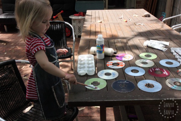 Toddler painting upcycled CDs