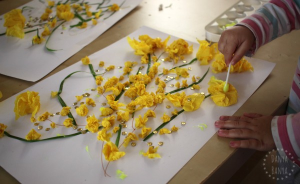 Toddler adding glitter glue (for added sparkle) to the Australian wattle collage