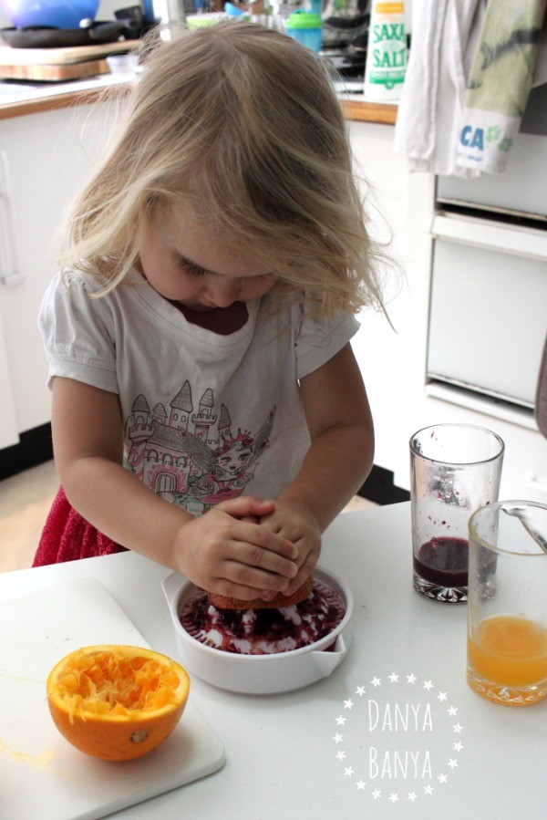 Three year old squeezing fresh blood orange juice